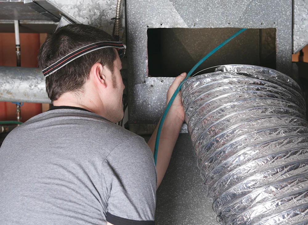 HVAC technician cleaning air duct